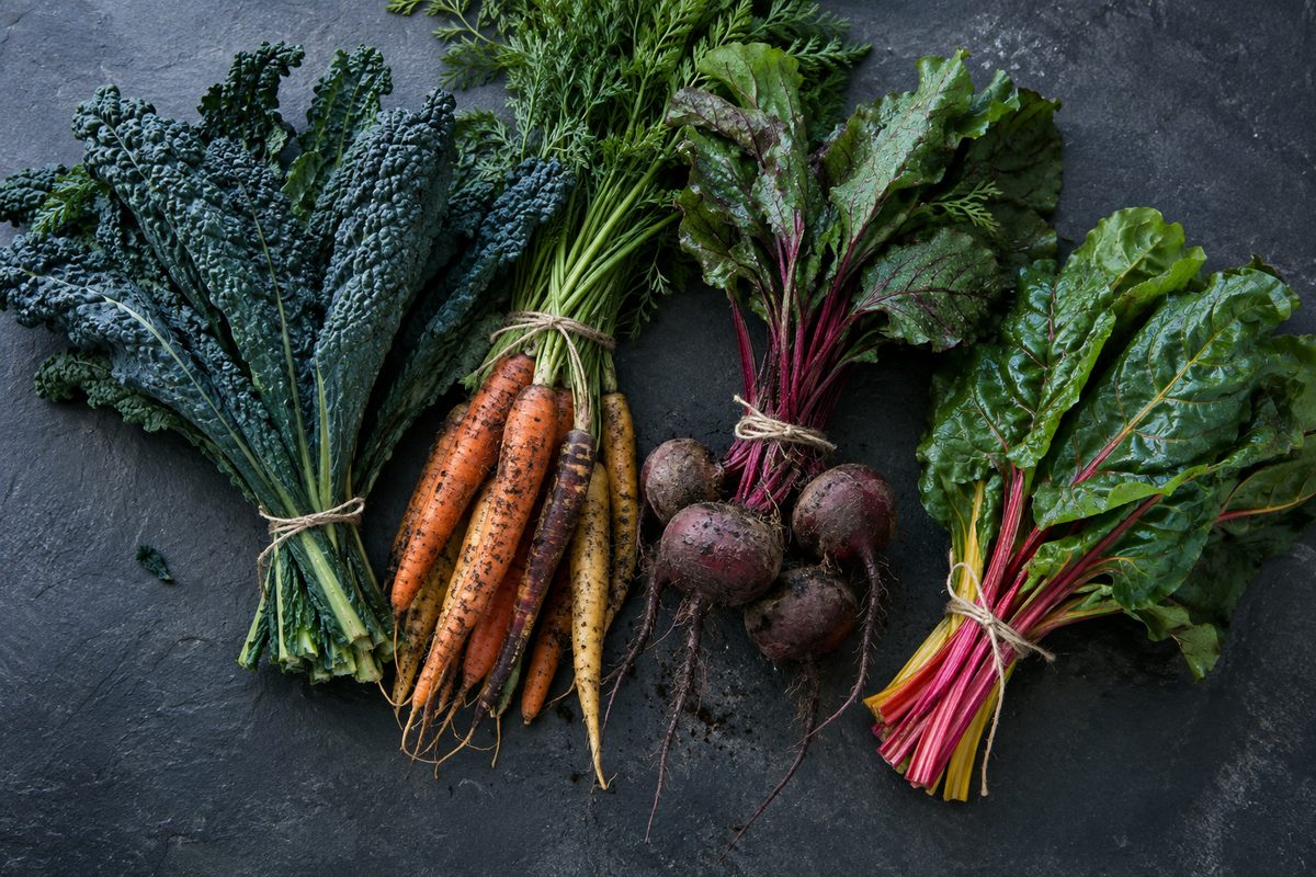 Lacinato kale, rainbow chard, carrots and beets with soil on the roots, tied with twine